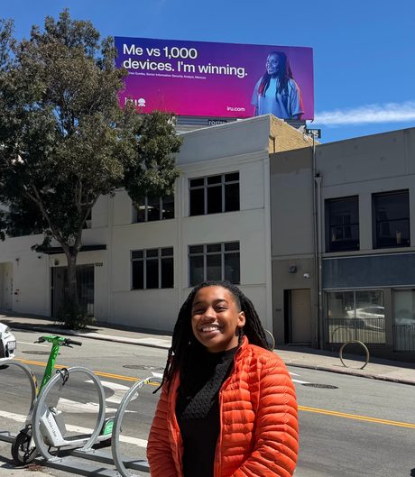 Sherise, founder of CampGuide, standing in front of a billboard for her security work